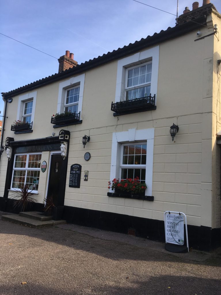 Cream painted pub exterior with black trim and flower boxes beneath the windows.