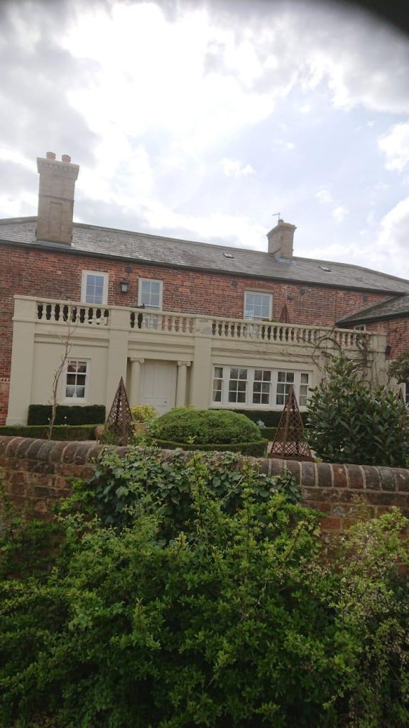 Red brick house with cream painted frontage and landscaped front garden.
