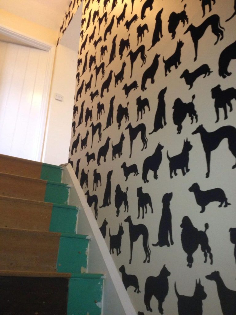 Feature wall with dog silhouette wallpaper beside a painted staircase with wooden steps.